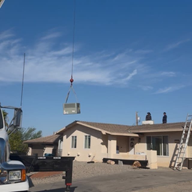 Crane lifting a replacement package unit over a Lake Havasu roof
